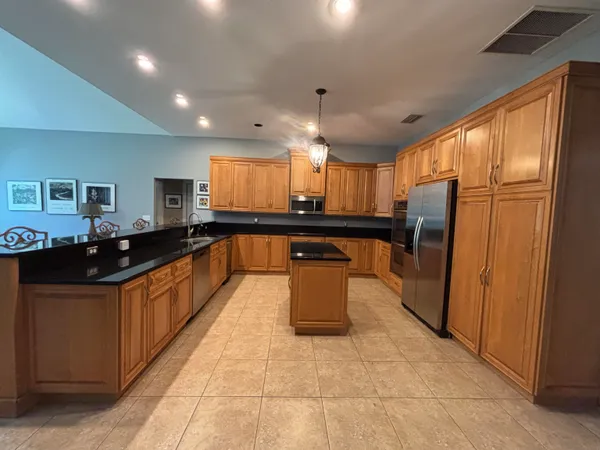 a large kitchen with stainless steel appliances kitchen island granite countertop a sink and cabinets