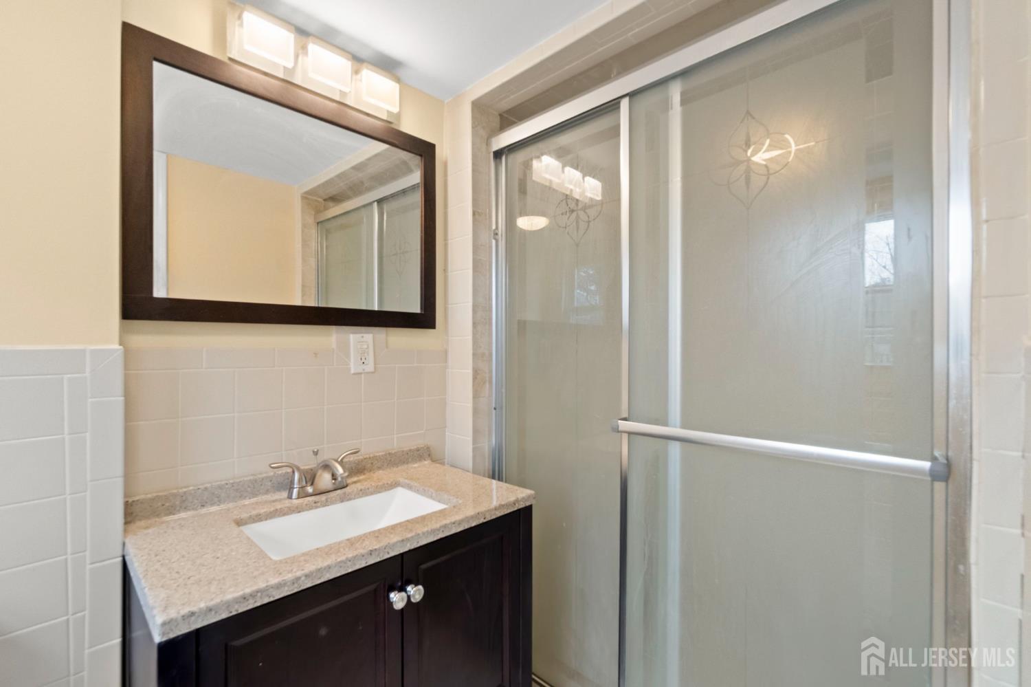 762 Valley Street Maplewood, NJ 07040 - Photo 20 of 21 a bathroom with a sink a mirror and a shower