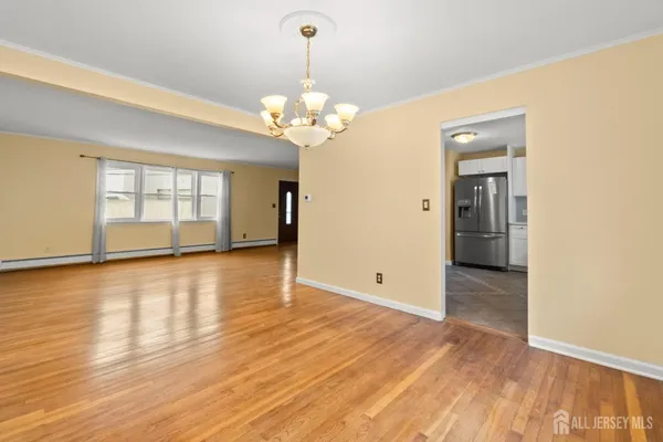a view of an empty room with window and wooden floor