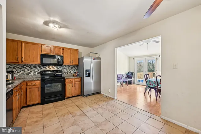 a kitchen with stainless steel appliances granite countertop a stove top oven a sink dishwasher a dining table and chairs with wooden floor