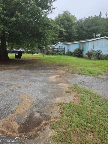 a view of yard with green space and trees in the background