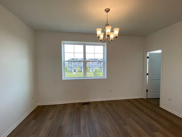 an empty room with wooden floor chandelier and windows