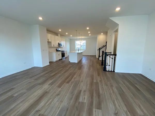 a view of a big room with wooden floor and a kitchen