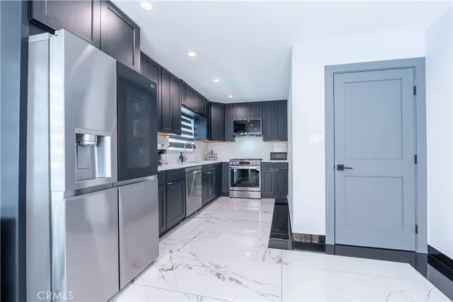 a large kitchen with stainless steel appliances kitchen island granite countertop a refrigerator and a sink