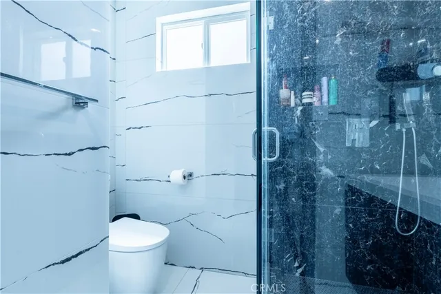 a living room with couches and kitchen view with wooden floor