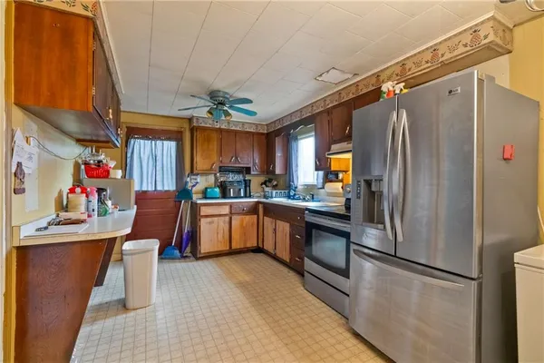 a kitchen with stainless steel appliances granite countertop a refrigerator a sink dishwasher a stove and a dining table with wooden floor