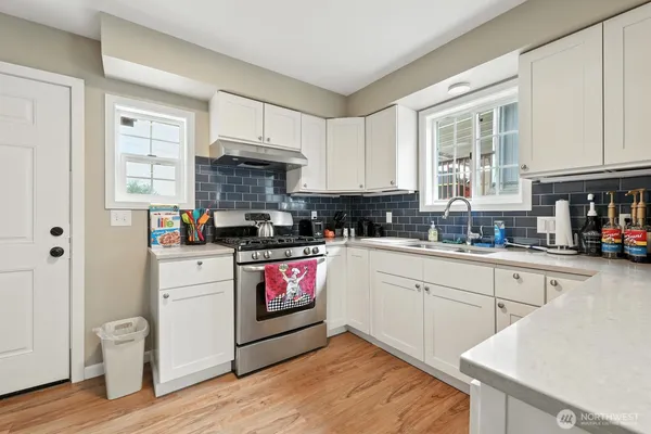 a kitchen with stainless steel appliances granite countertop a stove a sink dishwasher and a refrigerator with wooden floor