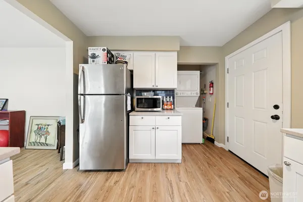 a kitchen with a refrigerator a stove top oven a wooden floor and a window