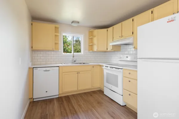 a kitchen with cabinets appliances a sink and a window