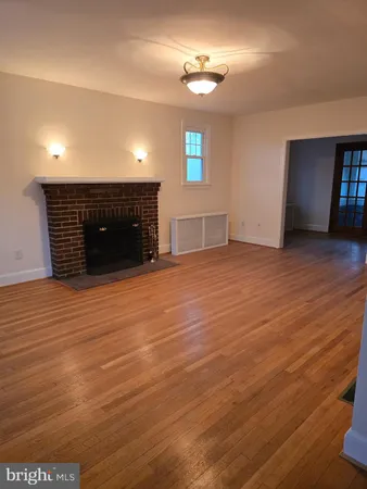 an empty room with wooden floor fireplace and windows