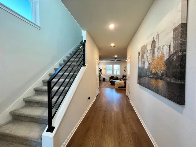 a view of a hallway with wooden floor and stairs