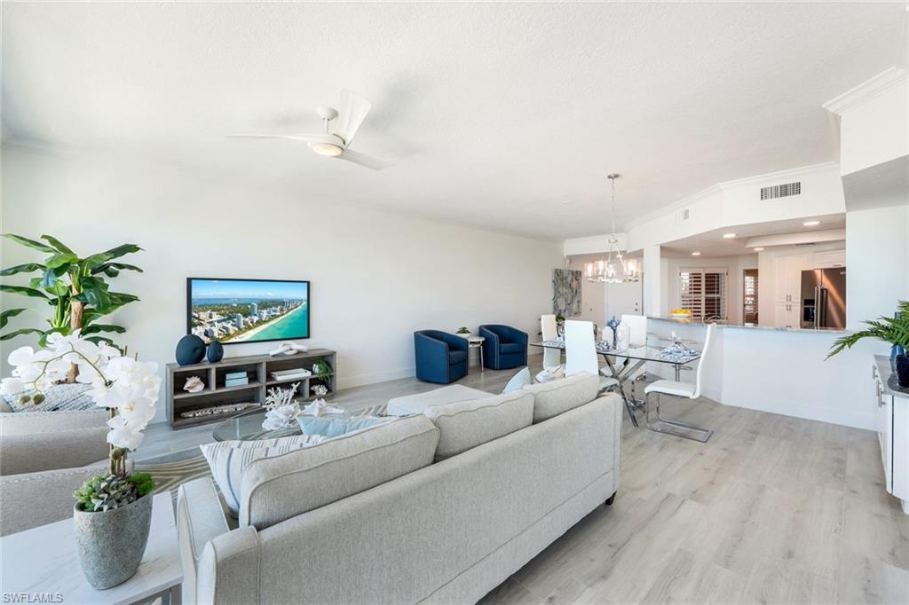 269 Barefoot Beach Boulevard, Unit 403 Bonita Springs, FL 34134 - Photo 11 of 27 Living room featuring a chandelier, light wood-style floors, baseboards, and ceiling fan