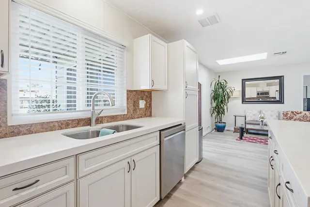a living room with furniture and kitchen view with potted plants
