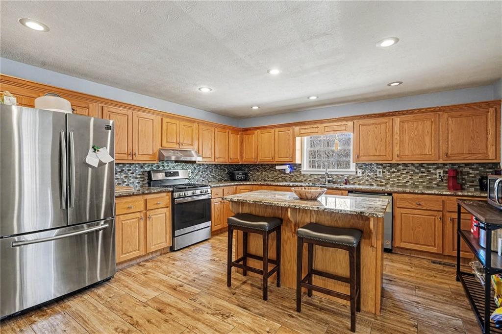 526 Antioch Church Road Talking Rock, GA 30175 - Photo 9 of 38 a kitchen with stainless steel appliances granite countertop a refrigerator a sink dishwasher a stove and white countertops with wooden floor