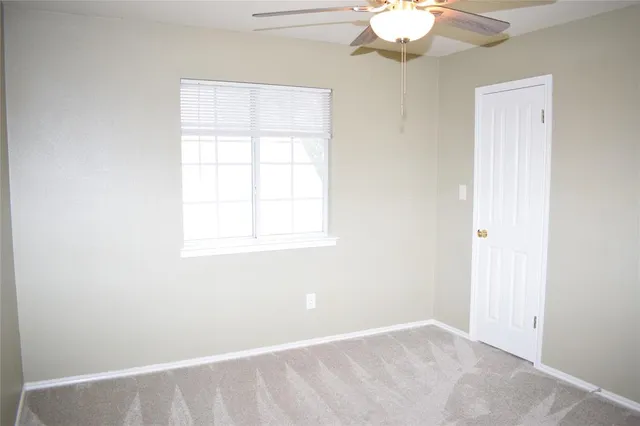 an empty room with a chandelier fan and window