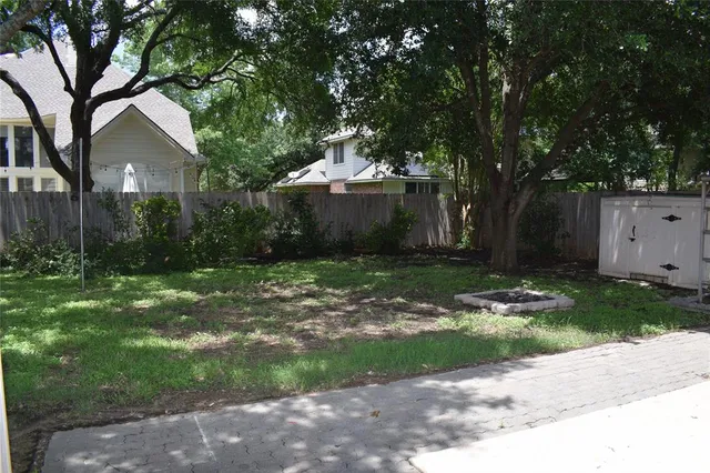 a backyard of a house with plants and large trees