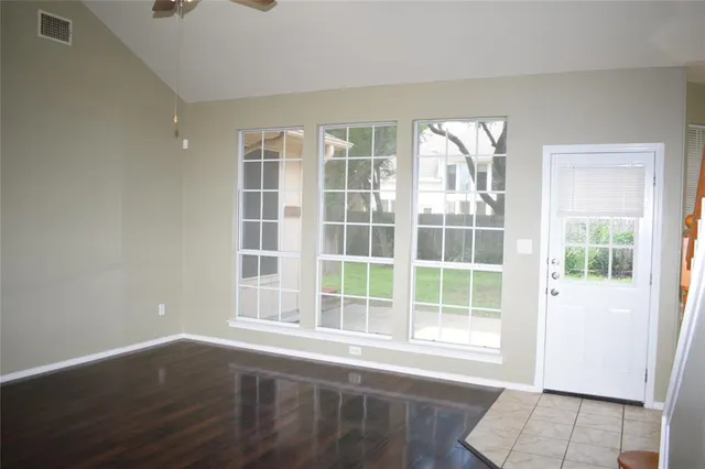 an empty room with wooden floor and windows
