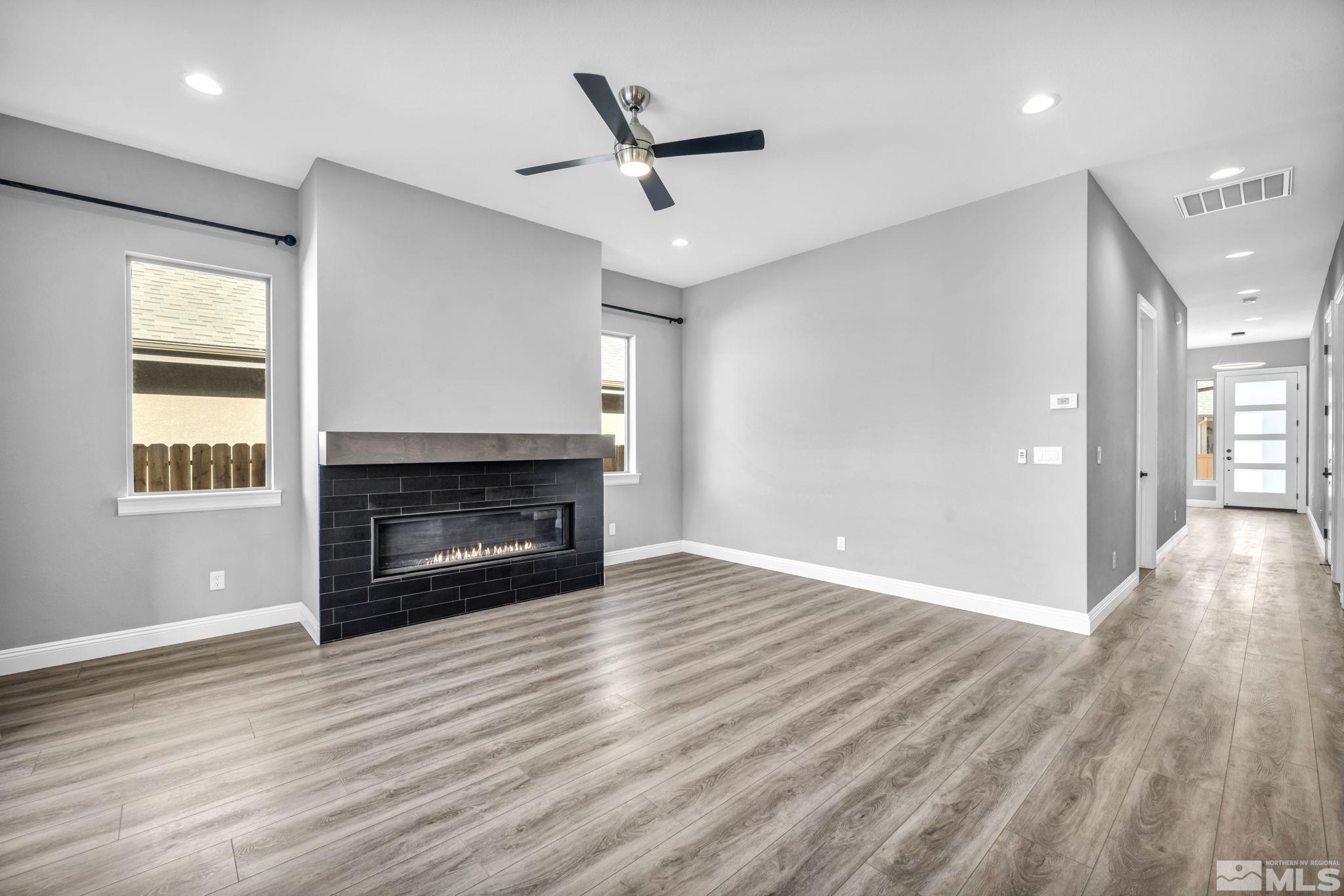 3108 Cambria Loop Carson City, NV 89703 - Photo 12 of 39 an empty room with windows a fireplace a ceiling fan and wooden floor