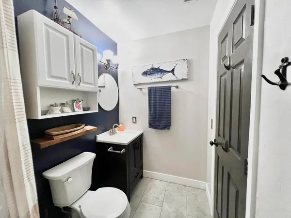 a bathroom with a toilet sink vanity granite and a mirror
