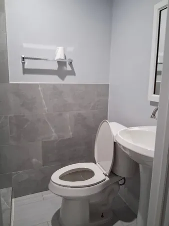 a white toilet sitting next to a bathroom sink and a mirror