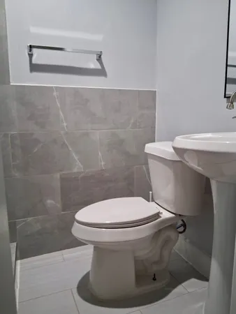 a white toilet sitting next to a shower