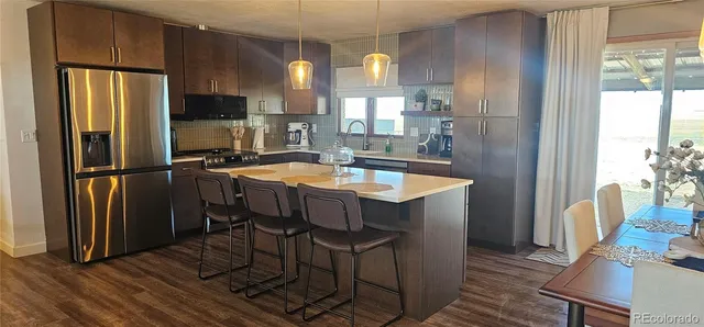 a kitchen with refrigerator a sink and chairs