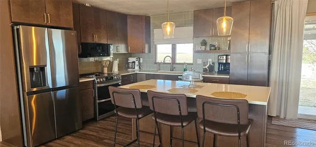 a kitchen with granite countertop a refrigerator a stove a sink dishwasher and white cabinets with wooden floor