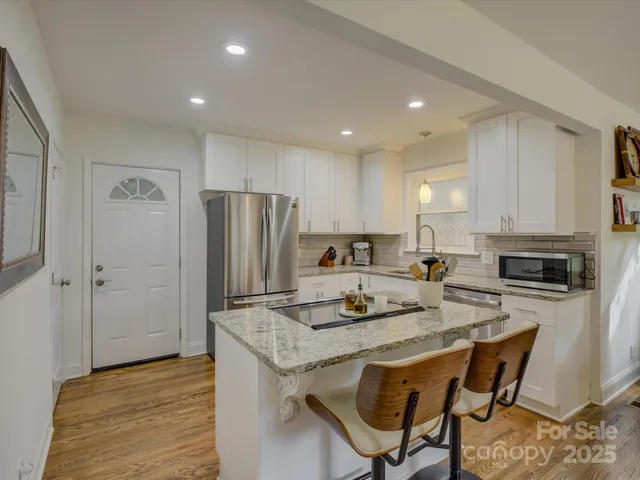 a kitchen with a refrigerator a stove a sink and white cabinets with wooden floor