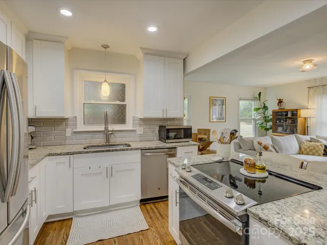 a living room with stainless steel appliances granite countertop furniture a sink a refrigerator and cabinets