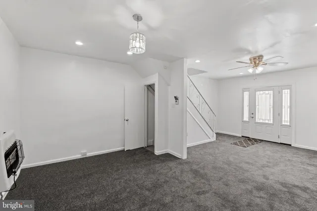 a view of an empty room with chandelier fan