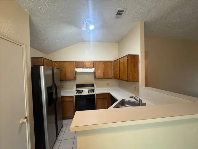 a kitchen with a sink stainless steel appliances a refrigerator and a stove top oven