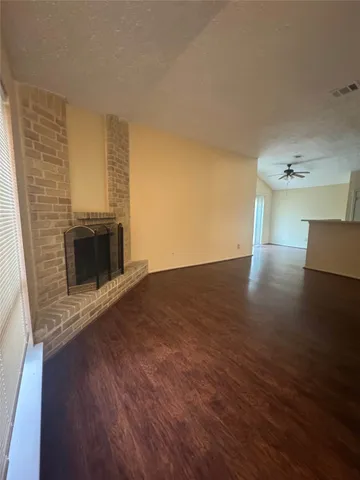 an empty room with wooden floor fireplace and windows
