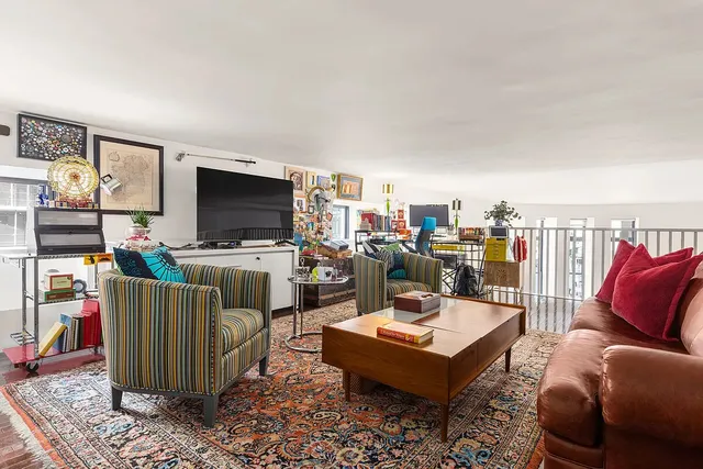 a living room with furniture a rug and a bookshelf