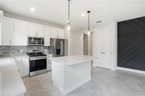 a kitchen with stainless steel appliances granite countertop a refrigerator a stove a sink and a microwave