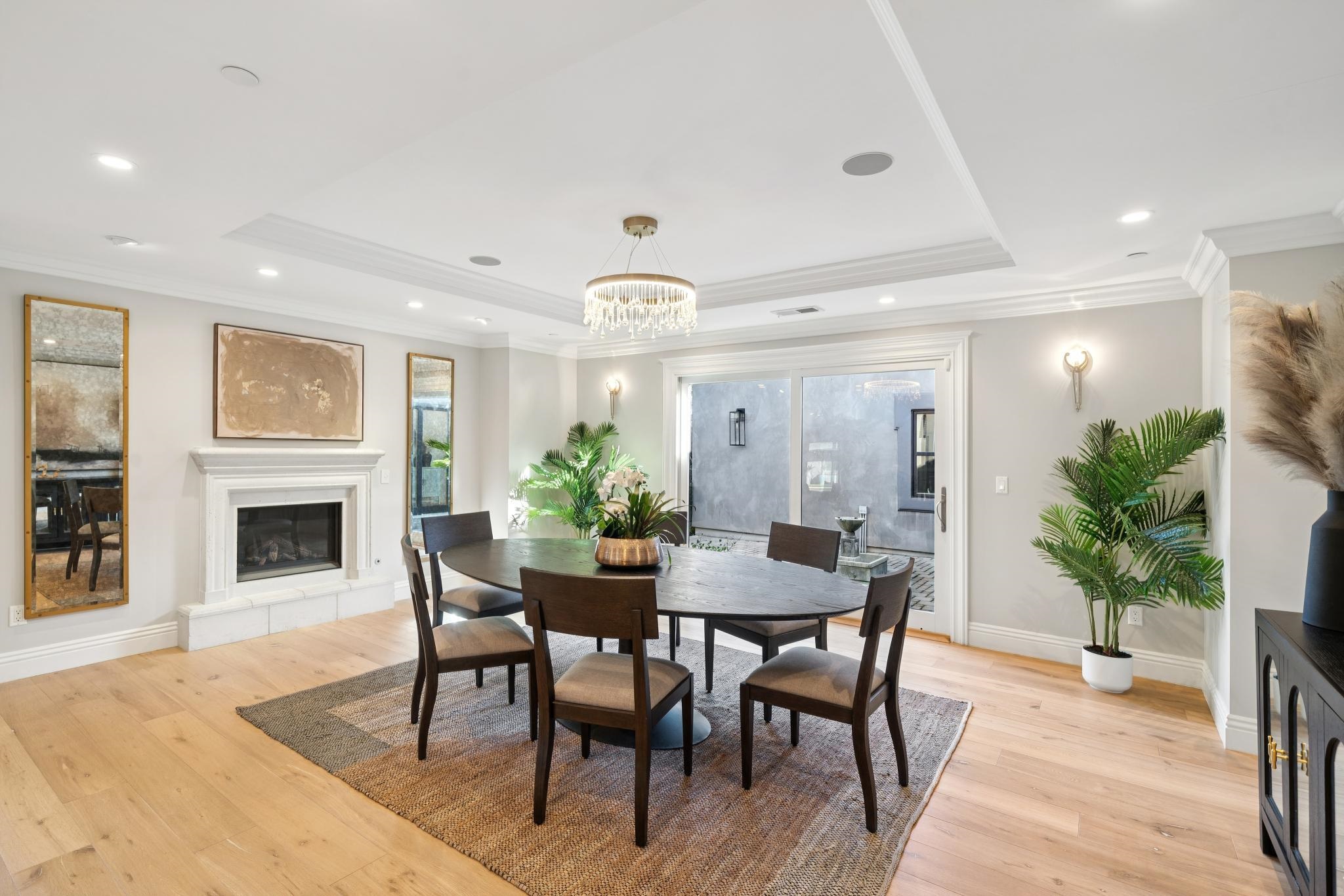3957 Rancho Road Lafayette, CA 94549 - Photo 8 of 60 Dining room featuring a glass covered fireplace, crown molding, light wood-style flooring, a raised ceiling, and a chandelier