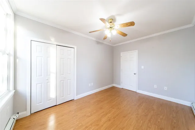 an empty room with wooden floor chandelier fan and windows
