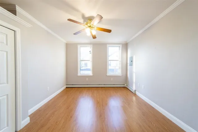 a view of empty room with wooden floor and fan
