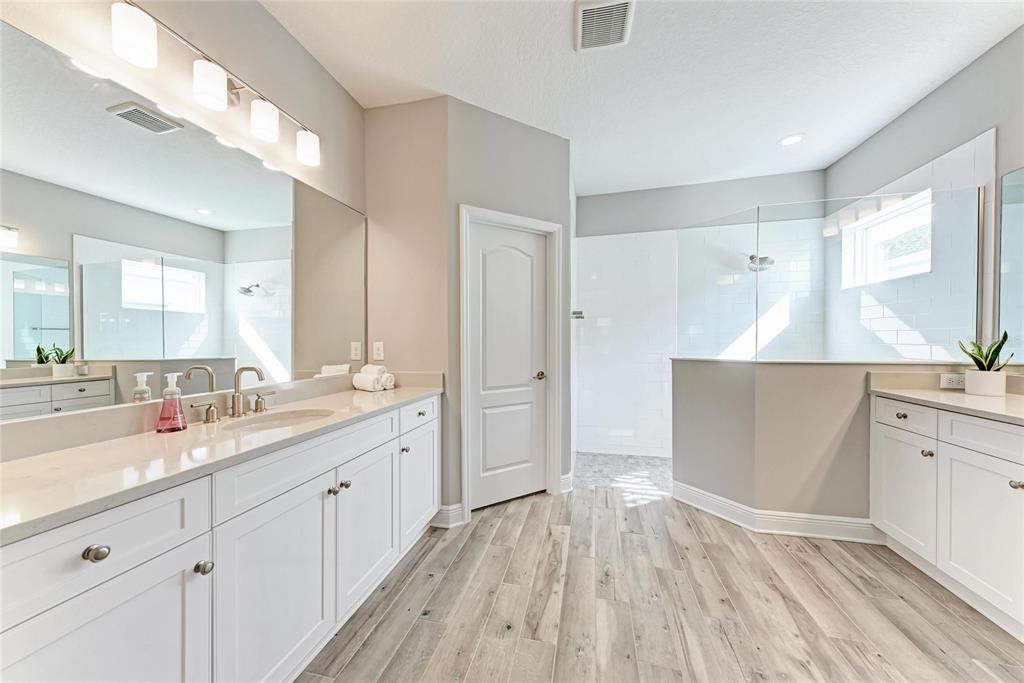 4211 Rustling Pines Terrace Parrish, FL 34219 - Photo 27 of 87 a kitchen with kitchen island a sink dishwasher a stove and white cabinets with wooden floor