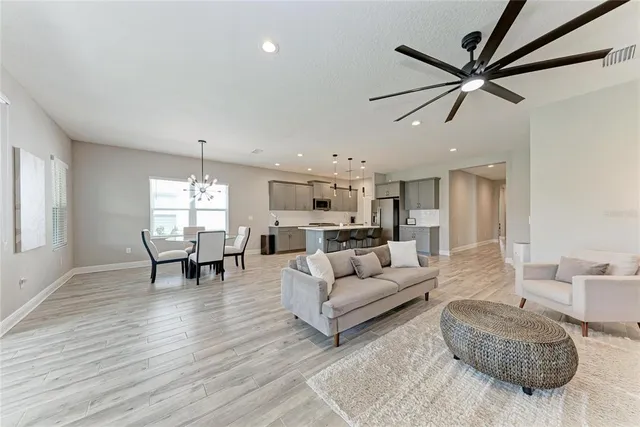 a dining hall with stainless steel appliances kitchen island granite countertop a table chairs and a refrigerator