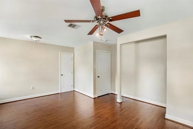 an empty room with windows and fan