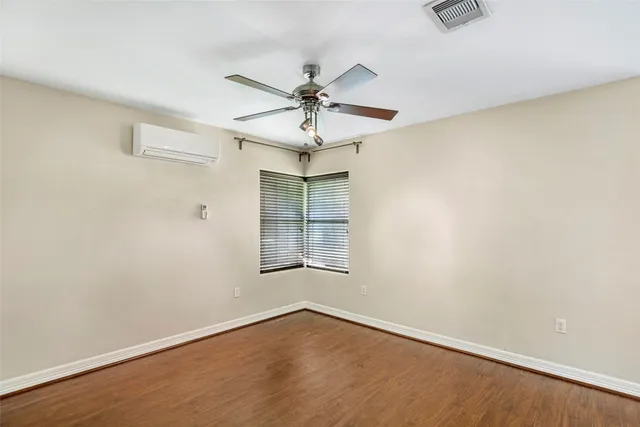 an empty room with wooden floor fan and windows