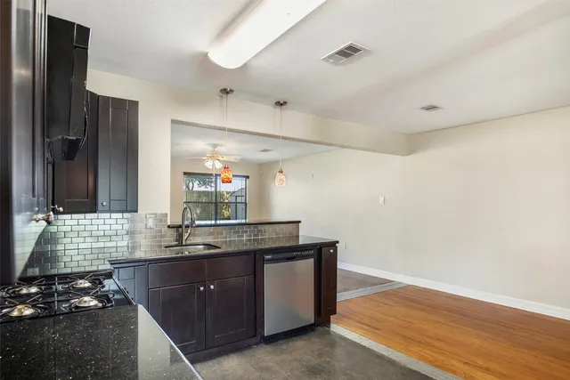 a kitchen with granite countertop stainless steel appliances a sink stove and cabinets