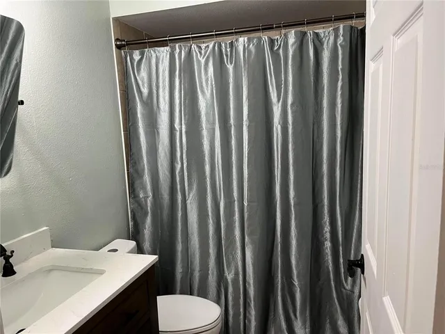 a bathroom with a sink a toilet and shower curtain