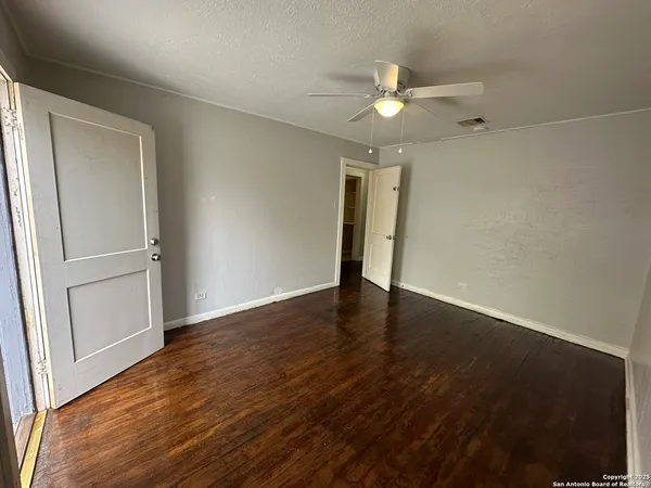 an empty room with wooden floor fan and window