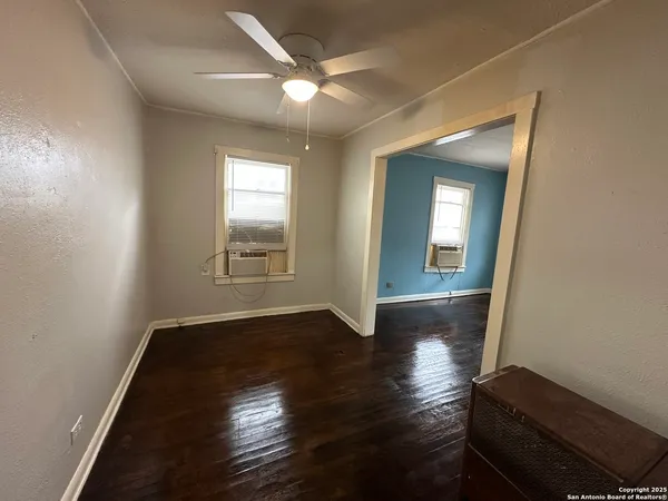 an empty room with wooden floor and windows