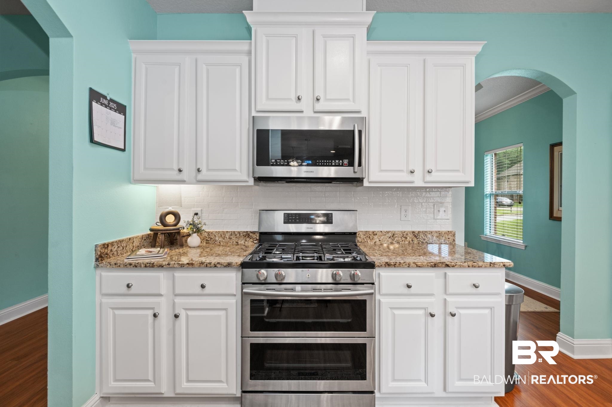 2554 Masters Court Mobile, AL 36618 - Photo 12 of 35 Kitchen with stainless steel appliances, arched walkways, wood finished floors, decorative backsplash, and white cabinetry