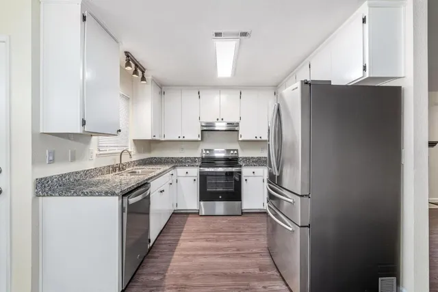 a kitchen with kitchen island granite countertop appliances cabinets and a sink