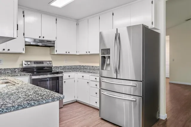 a kitchen with stainless steel appliances granite countertop a refrigerator and a stove top oven