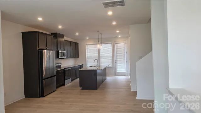 a kitchen with stainless steel appliances kitchen island granite countertop a refrigerator and a sink