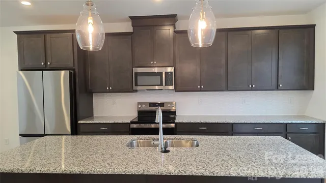 a kitchen with stainless steel appliances granite countertop a refrigerator and a stove